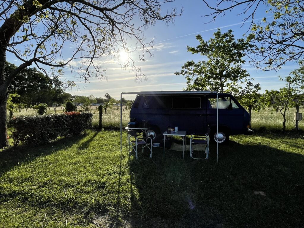 Van installé sur un vaste emplacement ombragé au camping dans les landes